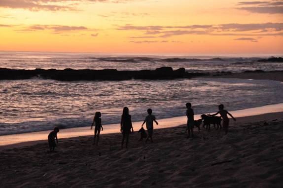 Durante o final de tarde, crianças e cachorros se divertem na praia de Santa Teresa, no litoral do Pacífico na Costa Rica